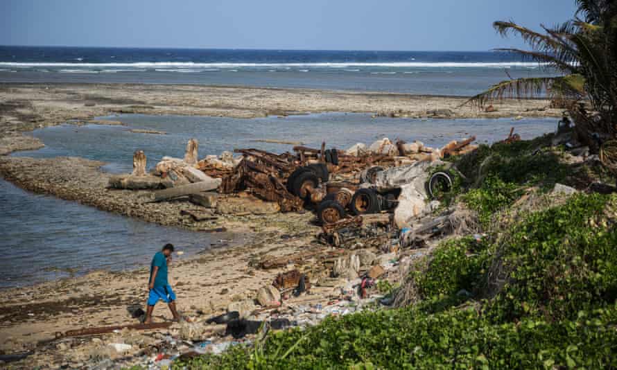A man walks along the eroded shoreline in the village of Jenrok, one of many places in the Marshall Islands affected by rising sea levels.