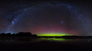 A stitched together photo of the aurora with the Milky Way bending overhead