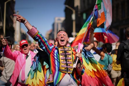 People are dressed in rainbow clothes cheering and waving