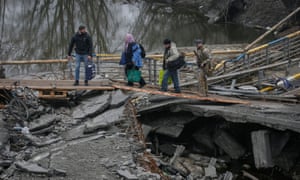 Tijdens de Russische invasie van Oekraïne buiten de Oekraïense stad Kiev op 1 april 2022, steken mensen de Irbin-rivier over bij de verwoeste brug bij het verlaten van de stad Irbin.