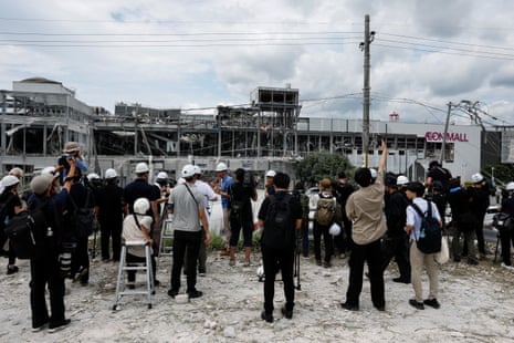 Members of the media stand near the damaged Aeon shopping centre.
