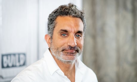 Man with beard wearing white buttondown looks at camera