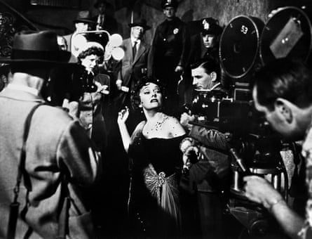 Imperiou-looking Gloria Swanson as Norma Desmond, surrounded by photographers and police in Sunset Boulevard.