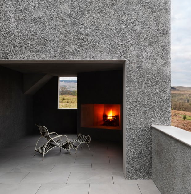 a semi exterior nook with burning fire in hearth and chair with landscape beyond