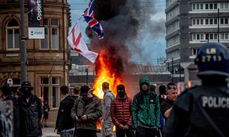 Masked protesters standing in front of fire