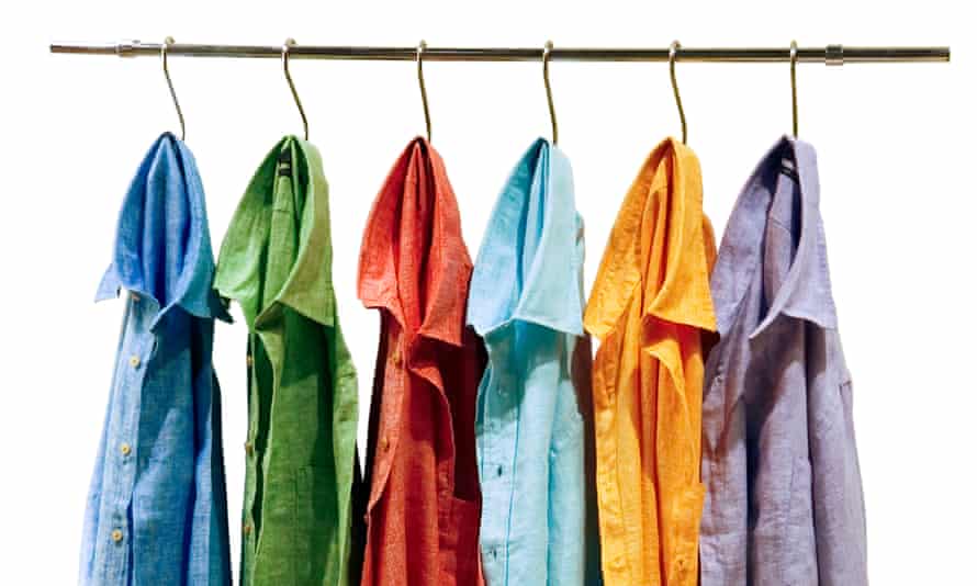 Six shirts of different colours are hanging on hooks on a metal rack