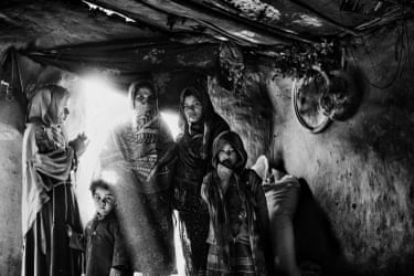A family standing closely together in a mud house with a low ceiling
