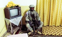 An armed soldier sits next to a TV. Rawa, Iraq, 2006