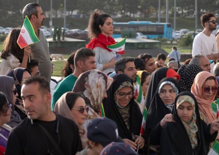 A young Iranian woman holds a country’s flag as she stands at Azadi Square to watch a live concert in western Tehran, Iran.