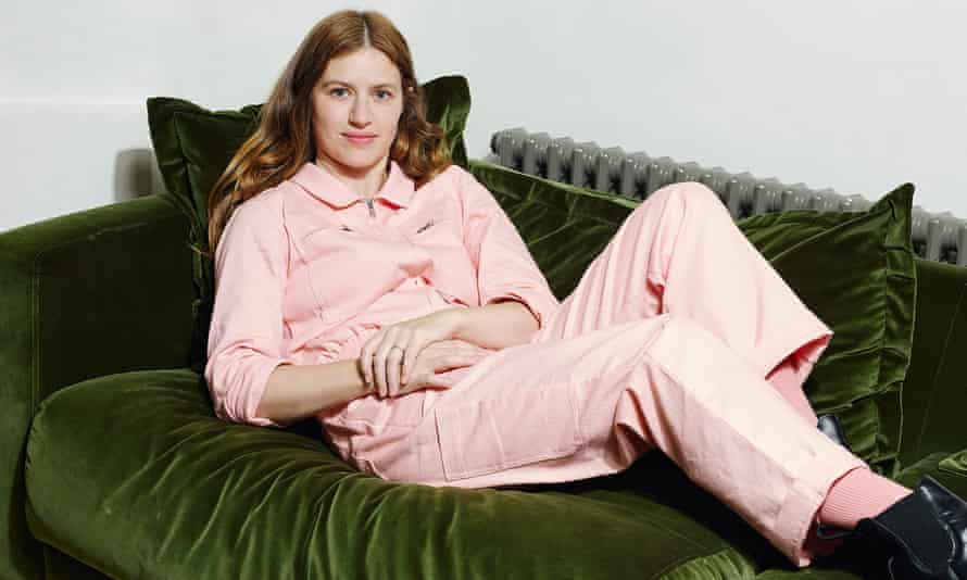 Louise Markey, Founder of LF Markey, photographed on a velvet green sofa in her home in a pink junpsuit.