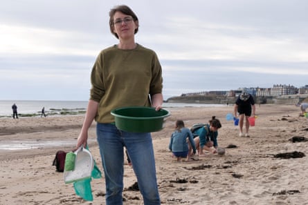 Alice Laverty stands on a beach with a bucket in her hand