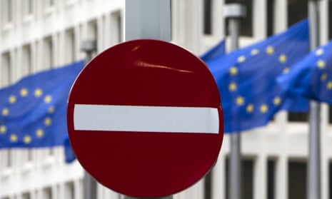 EU flags flutter behind a no entry street sign