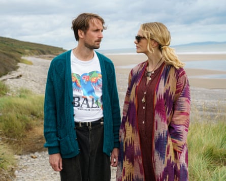 Man and woman stand on grass near beach