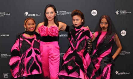 A woman standing for a group photo with three girls on the red carpet, all wearing complementary pink and black outfits