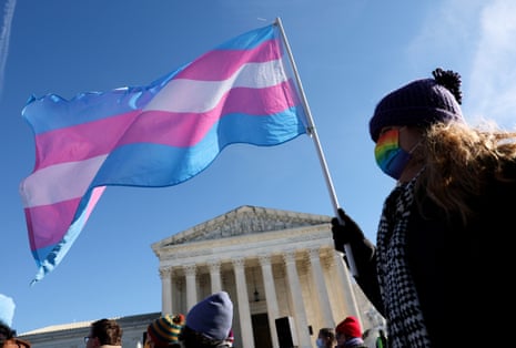 a person holds a blue pink and white flag outside