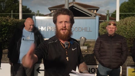 Tommy Robinson with outgrown hair and beard speaks to the camera flanked by his entourage