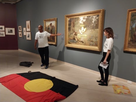 Activists stand in front of the Frederick McCubbin painting Down on his luck which has been spraypainted with the Woodside logo at the Art Gallery of Western Australia