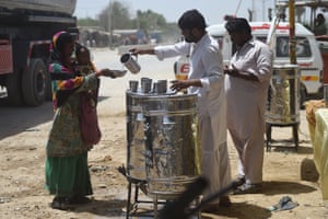 Volunteers distribute water to a woman and child in Karachi, Pakistan