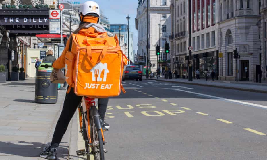 A Just Eat courier rides along Piccadilly Circus delivering takeaway food in central London.