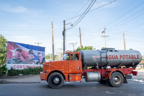 A potable water tanker truck drives through the municipality of Cotorro, in Havana, past a billboard featuring the leaders of the Cuban Revolution