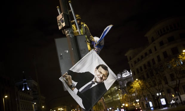 A worker removes a campaign poster for the national elections depicting Spain’s Prime Minister and Popular Party candidate Mariano Rajoy, in Madrid.