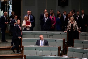 Scott Morrison sits alone in the House of Representatives as colleagues stand behind him