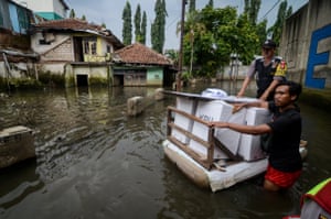 Officials carry election materials on a raft in a flooded area of Bandung, Indonesia