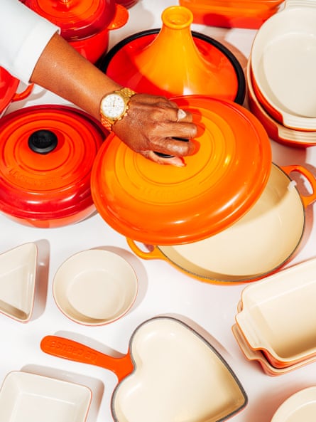 woman’s hand lifting lid of orange le creuset pot