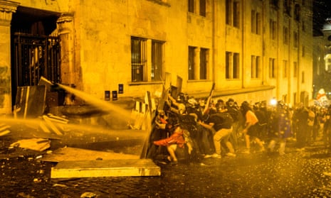 Demonstrators block the Georgian parliament building entrance amid efforts by riot police to disperse the crowd using tear gas and water cannon on 1 May in Tbilisi.