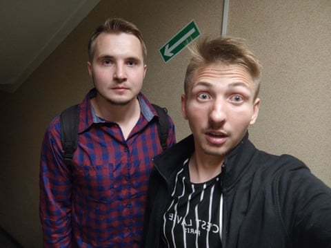 Two young men stand at the top of a flight of stairs. One has his eyebrows raised and eyes wide.