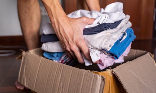 Putting clothes in a cardboard box to donate