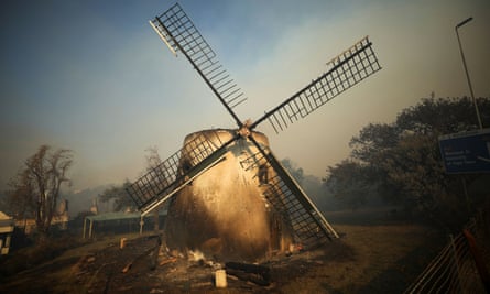 The historic Mostert’s Mill smoulders as firefighters battle to contain a fire, in Cape Town