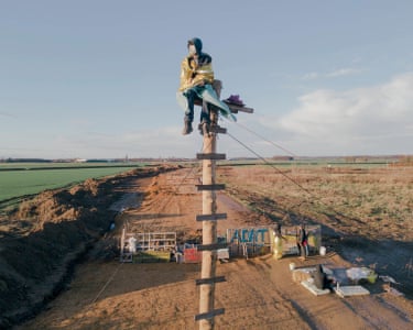 An activist sits on a pole to try to stop the construction of an access road