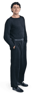 A curly, dark-haired man stands, hands in pockets, wearing all black