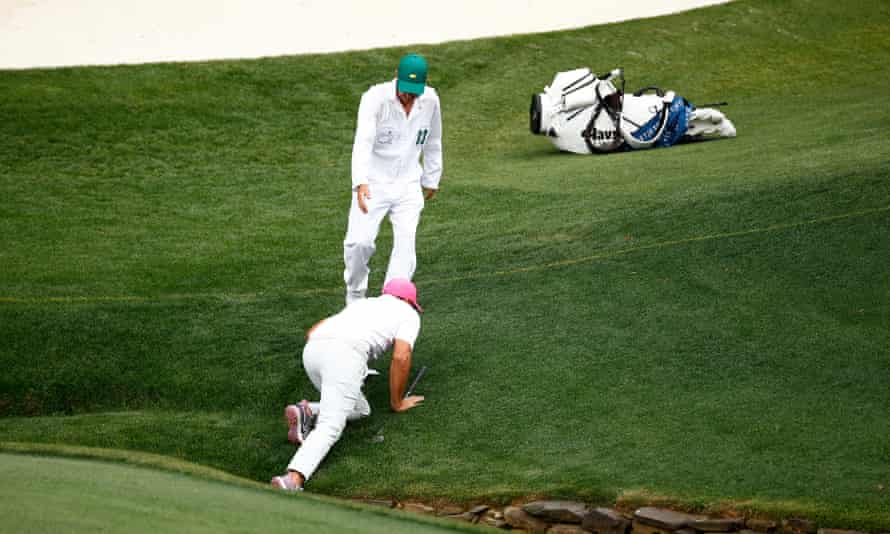 Brooks Koepka is helped out of the creek by his caddy, Ricky Elliott, on the 13th hole.