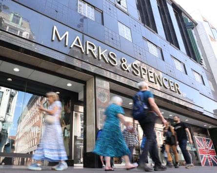 Shoppers pass a Marks & Spencer retail store in London