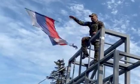 man hurls flag from top of metal structure