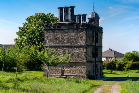 A compact building of worn grey bricks with large chimneys and a turret.