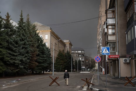 A man walking on a street with barricades in Kharkiv.