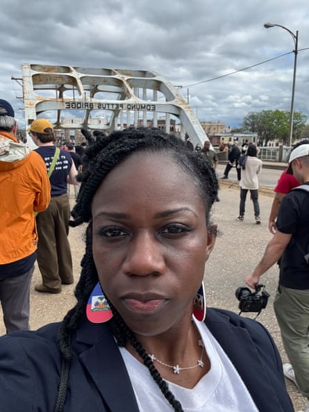 A woman takes a selfie outside while people gather near her