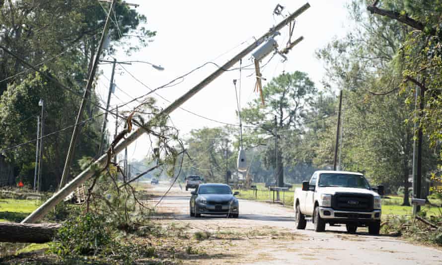 Cars drive past fallen utility poles in Jennings, Louisiana, on 10 October.