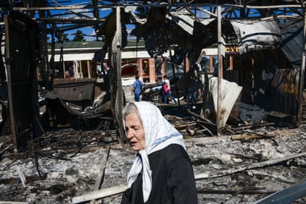 A woman in a white headscarf passes by damaged structures