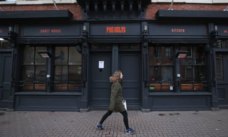 A woman walks past a closed bar in Belfast during Northern Ireland’s national lockdown.