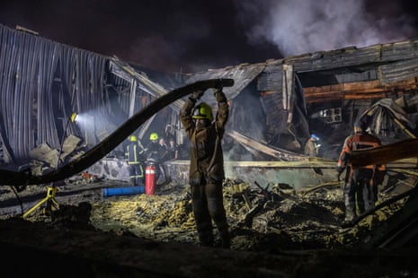Rescue crews lift debris surrounding the destroyed shopping centre in Kremenchuk.