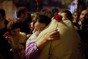 A couple hold red carnations while embracing each other after thousands sang the folk song Grandola, Vila Morena