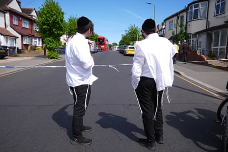Two Jewish men stand at the cordoned off area in Golders Green.