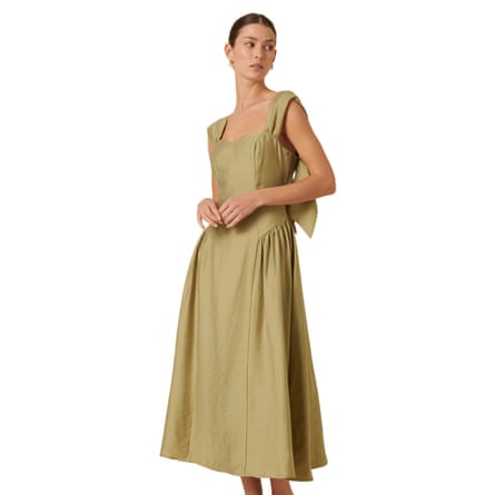 The model wears a bodice style sage green dress with their hands in front of their waste.