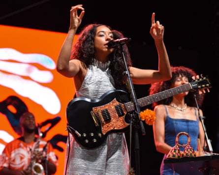 A woman raises her arms on stage as she performs.