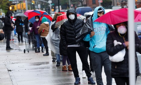 People wear protective face masks as they wait in line to receive free food in the Brooklyn borough of New York.