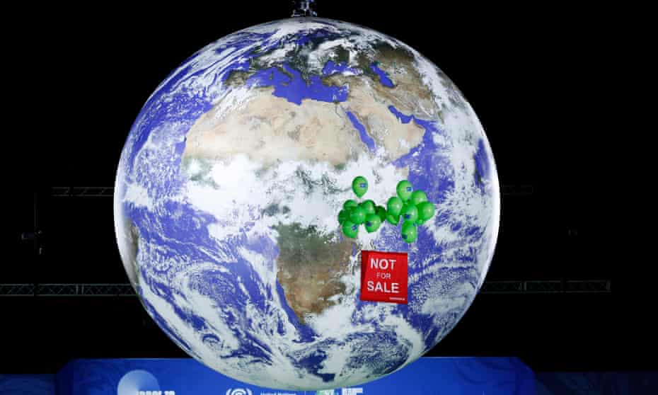Demonstrators raise a banner in front of a giant globe in the final hours of the UN Cop26 climate summit in Glasgow.